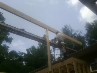 Carpenter setting a ridge beam over a new addition frame — Ice Dam Removal by Roofing Brothers in Munday