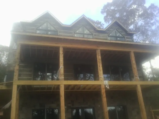 Dormers and porch framing on a large log home under construction — Roof Coating work by our crew in Munday