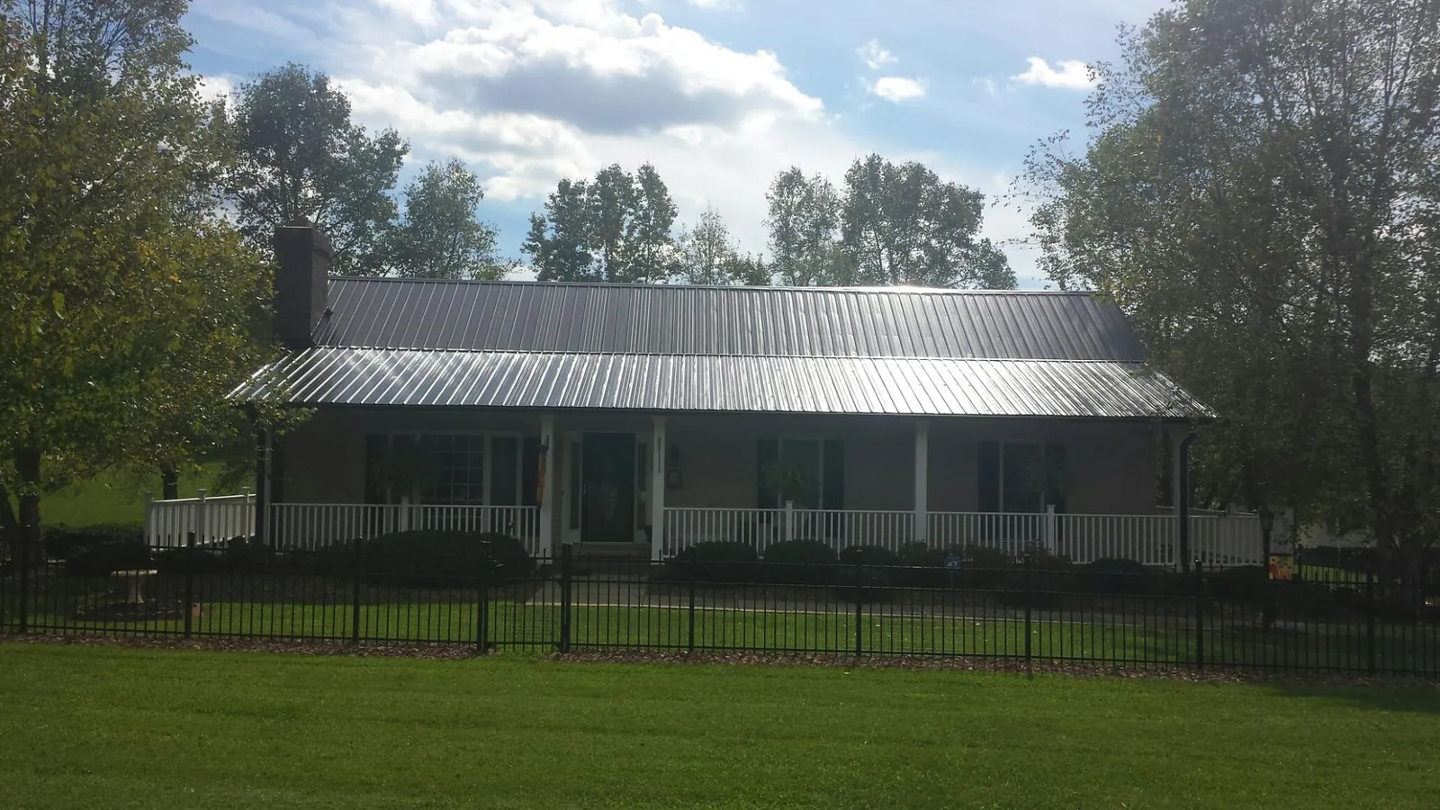 Gray metal roof on a brick ranch with a full width front porch — Gutter Guard Installation work by our crew in Munday