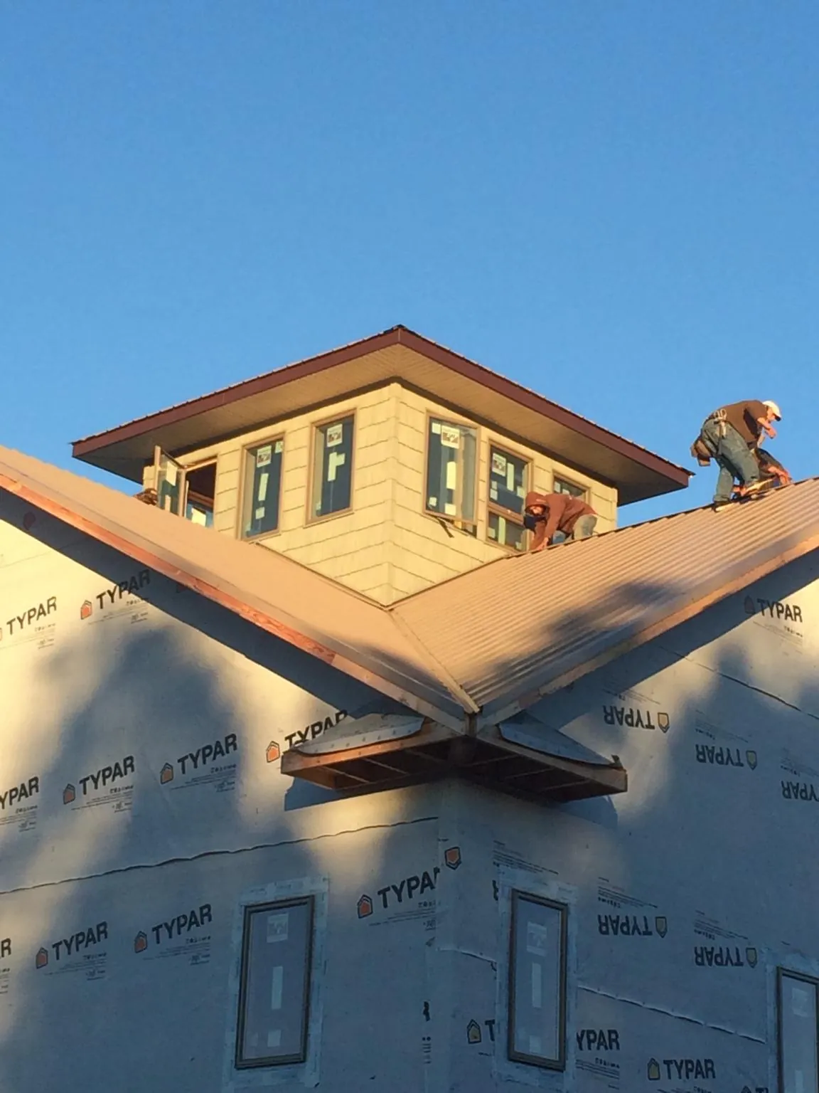 Roofers working around a rooftop cupola on a new metal roof at sunset — Roof Waterproofing in Munday by Roofing Brothers